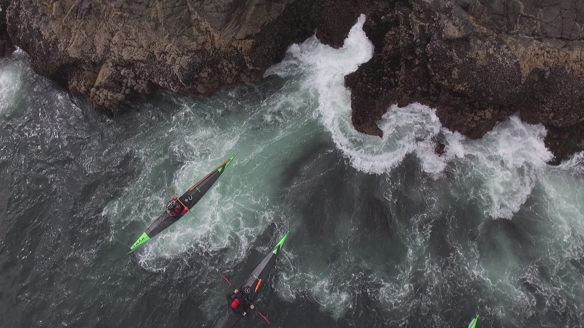 Load video: Paddlers in TRAK folding kayak navigating waves near rocky coastline
